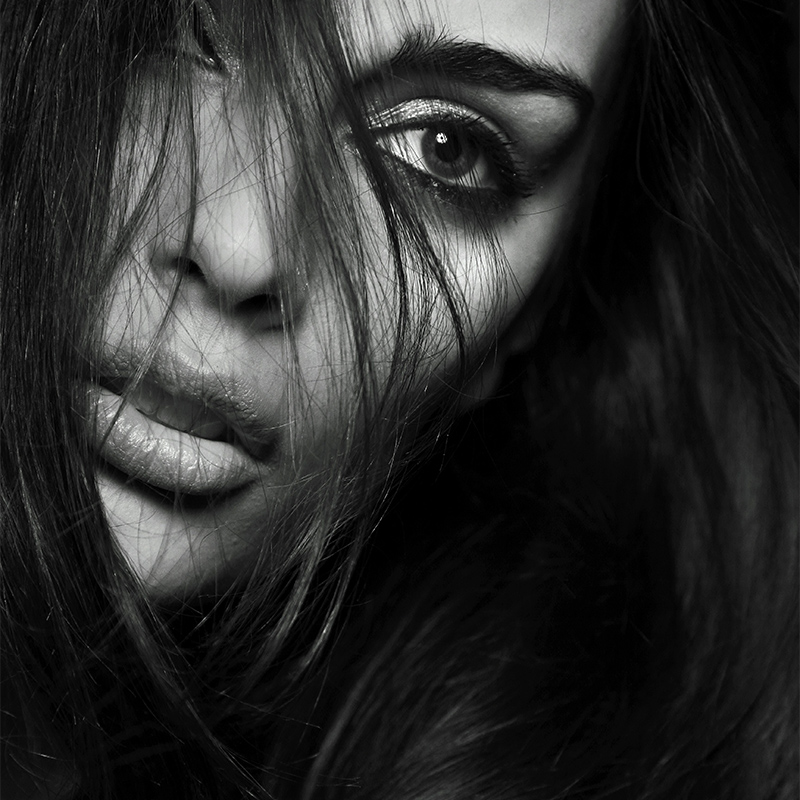 black and white photo of dark haired woman with feathered